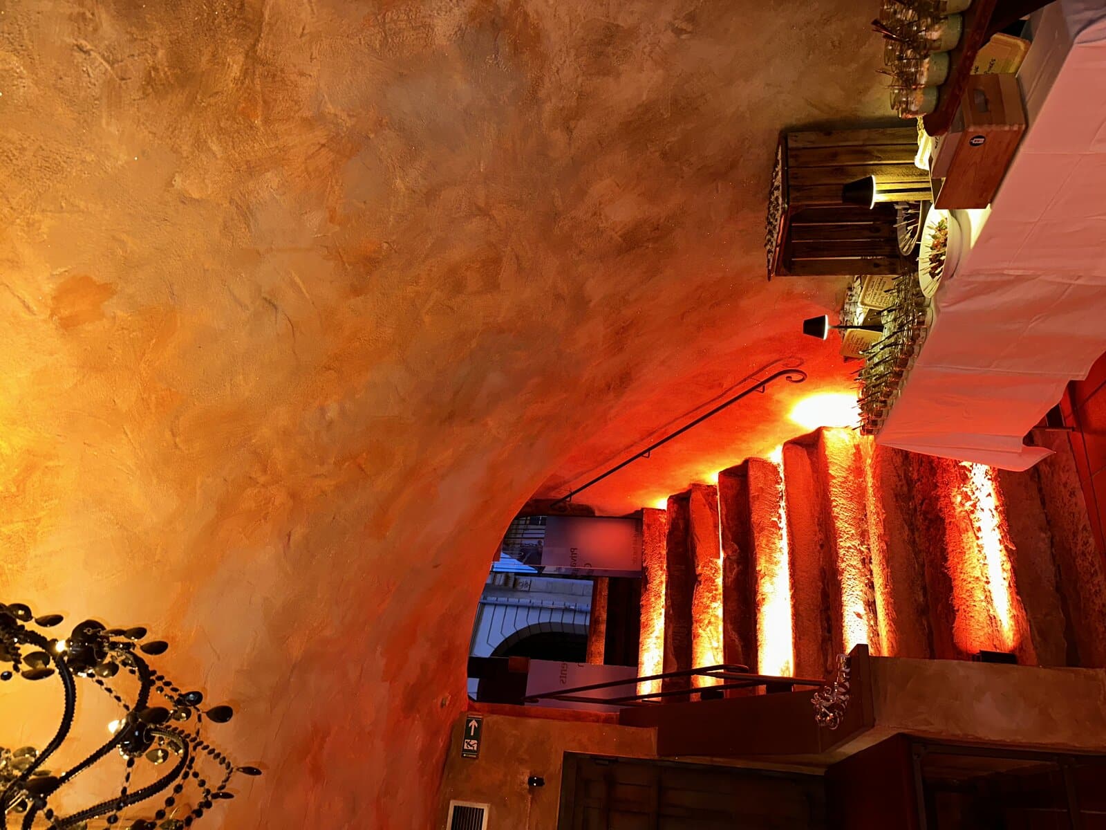 Eleganter Lounge-Bereich mit Kronleuchter und beleuchteten Säulen im Gewölbekeller der D48 Bar